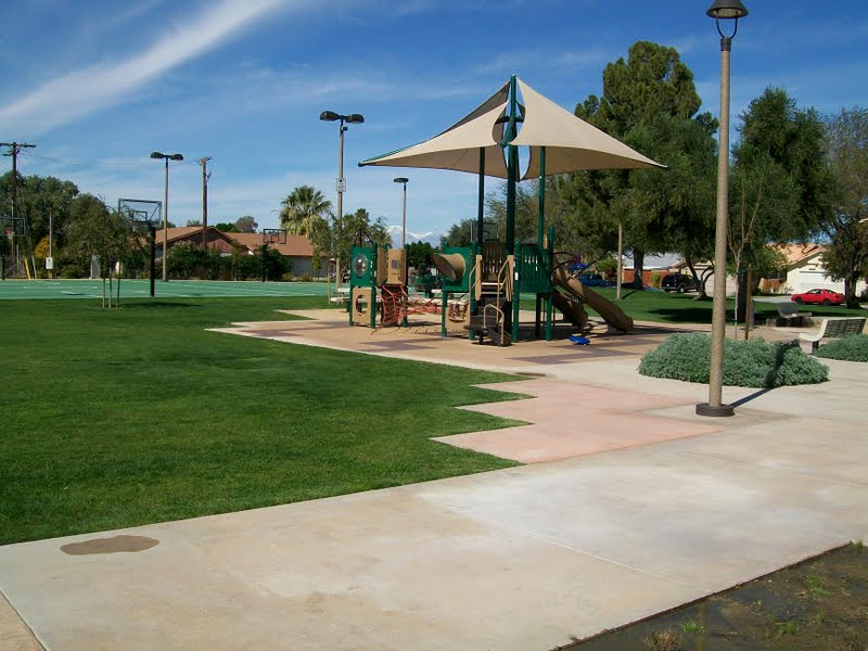 Playground surrounded by maintained lawn, pathways, and low planting