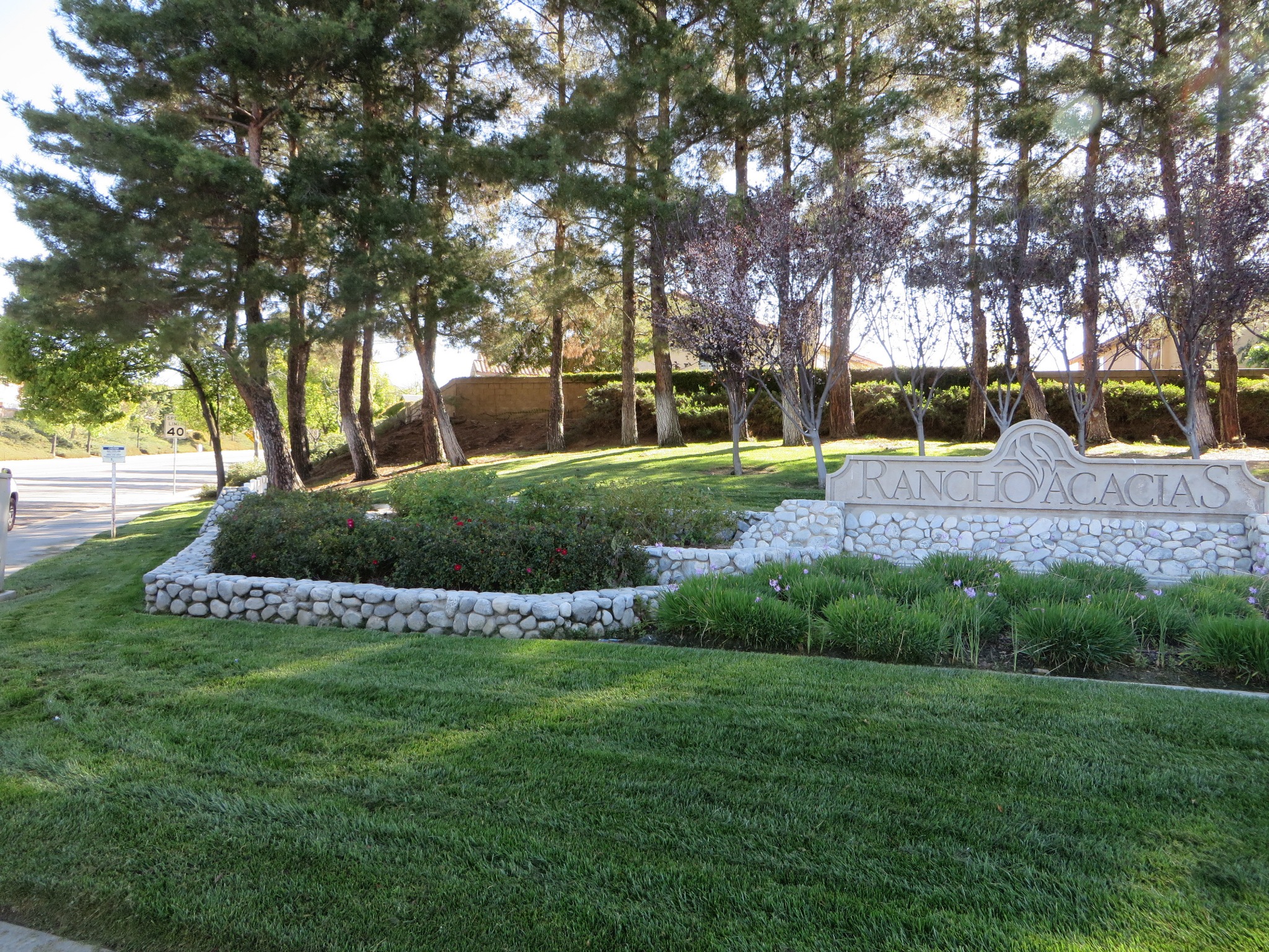 Rancho Acacias community monument surrounded by maintained lawn, trees, and planting